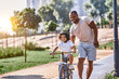 © Afshar Tetyana - Cheerful curly kid cycling with his father by his side