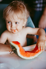 Wall Mural - Happy toddler boy eating watermelon in his highchair