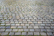 Neat paving stones with stones slightly wet from the rain. Wet pavement. Old cobblestone road, selective focus.