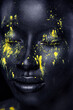 © Mike Orlov - Woman with black body paint. Cheerful young african girl with art bodypaint. An amazing model with yellow makeup. Closeup face.