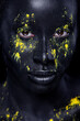 © Mike Orlov - Woman with black body paint. Cheerful young african girl with art bodypaint. An amazing model with yellow makeup. Closeup face.