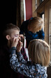 © Julia Forsman/Stocksy - A little girl applies lipstick on her brother while their cousin looks on.