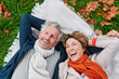 © IVAN GENER/Stocksy - Laughing mature couple lying on grass