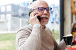 © IVAN GENER/Stocksy - Smiling senior man talking on a phone in a cafe