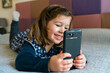 © Giorgio Magini/Stocksy - Joyful preschool girl using smartphone with pleasure while chilling at home