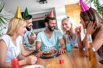 Birthday cake and group of friends at party.