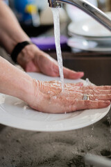  primer plano de manos lavando vajilla platos cubiertos copas de cristal esponja y jabon 