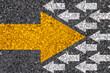 © Dilok - Different thinking and Business and technology disruption concept. Yellow big arrow opposite  direction with white arrow on road asphalt.