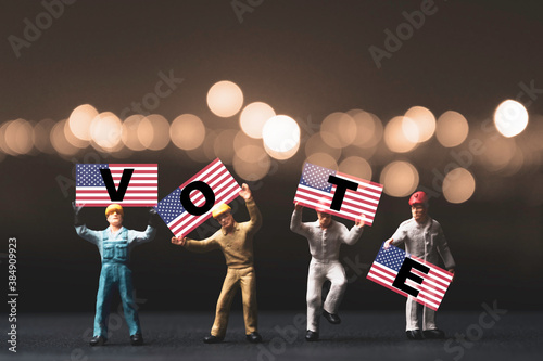 Fotografía Voter and USA election concept , Worker showing USA flag which print screen VOTE wording on flag