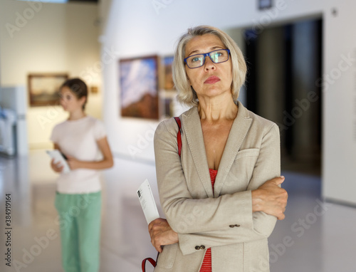 Attentive mature woman observing exhibition in art museum