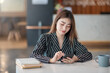 © amnaj - Young pretty asian woman using a smartphone and sitting at working in the office.