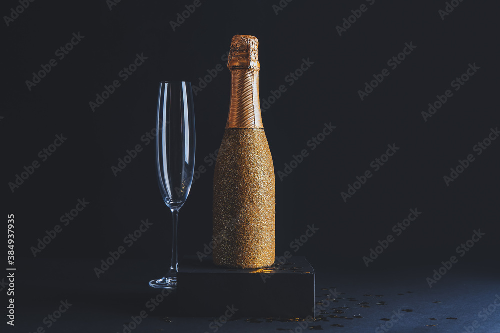 Bottle of champagne and glass on dark background