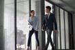 asian business man and woman walking talking in office