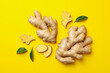 Fresh raw ginger with leaves on yellow background