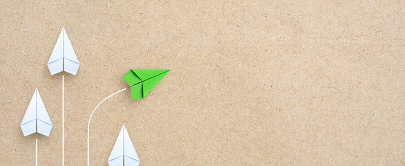 Wall Mural - Group of white paper plane in one direction and one green paper plane pointing in different way. Business for innovative solution concept, copy space