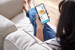 © Pixelated 275 - women holding phone with application delivery food online sit on couch at home