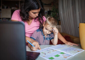 Wall Mural - Distant education. Mother doing online homework with her little son at home, family lifestyle