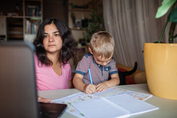 Wall Mural - Distant education. Mother doing online homework with her little son at home, family lifestyle