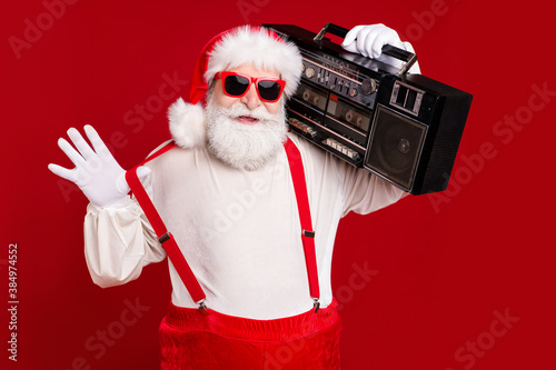 Portrait of his he handsome cool confident bearded Santa dj deejay hipster carrying retro tape boombox having fun rest relax chill celebratory isolated bright vivid shine vibrant red color background