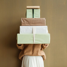 Young Beautiful Woman Hold Paper Gift Boxes Stack Against Olive Wall. Festive Christmas / New Year Holidays Celebration Concept.