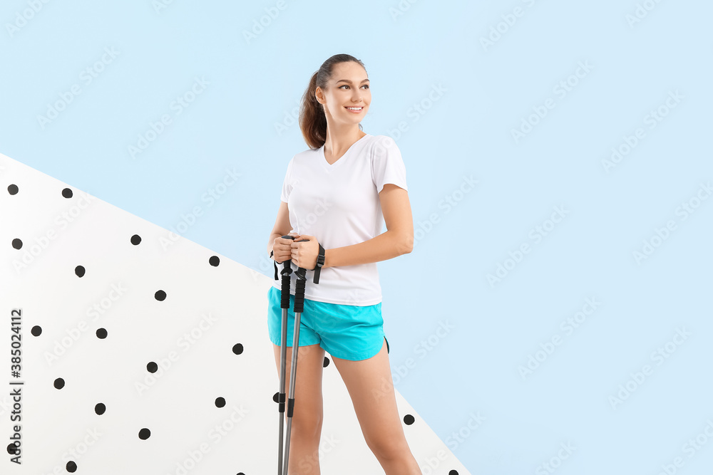 Young woman with walking poles on color background