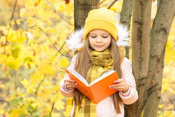 Wall Mural - A child leans against a tree and reads the book autumn.