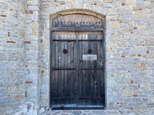 Medieval Wooden Heavy Door On A Stone Wall. Stone Strong Walls And Surroundings. Ancient Stone Ground.