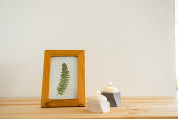 two concrete candlesticks with a frame on a wooden shelf