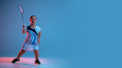 Wall Mural - Motion. Beautiful dwarf woman practicing in badminton isolated on blue background in neon light. Lifestyle of inclusive people, diversity and equility. Sport, activity and movement. Copyspace, flyer