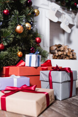 Canvas Print - Selective focus of gift boxes near pine and fireplace with christmas stockings