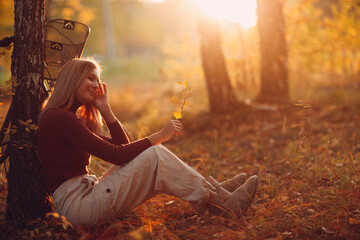 young woman sitting near tree with vintage bicycle in autumn park at sunset