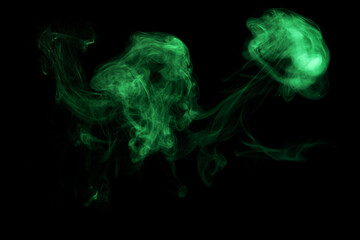 Luminous isolated abstract chaotic puffs of smoke on dark. Green smoke on black background.