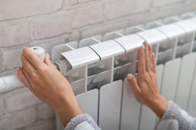 Close-up Of A Female Hand Regulating The Temperature Of A Heating Radiator