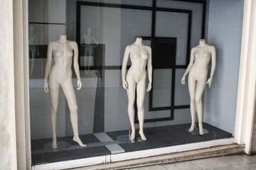 The window of empty clothing store in the commercial center of Athens, with mannequin dolls in the display - Athens, Greece, October 9 2020.