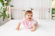 © Any Grant - cheerful baby girl six months crawling in a bright beautiful room on a white bed in pink clothes and smiling