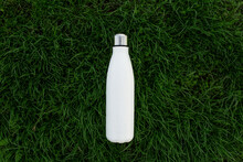 Top View Of Reusable, Eco Steel Thermo Water Bottle Of White Color On Green Grass.