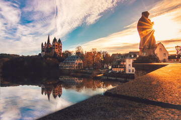 The cathedral in Limburg Germany.  nice view over an old bridge with statue and the river at sunrise