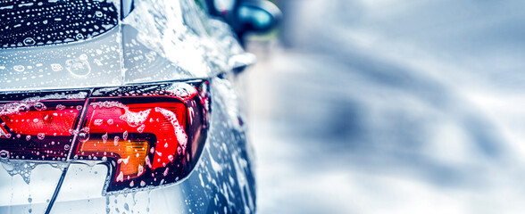 Manual car wash with white soap, foam on the body. Washing Car Using High Pressure Water.