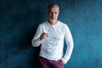 Wall Mural - Casual Grey-haired Mature handsome man portrait over dark blue wall background