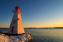 Red And White Lighthouse Looking Out On A Flowing Lake During A Warm, Winter, Sunset With Clear Skies, In Charlottetown Prince Edward Island, Canada