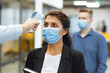 © Konstantin Zibert - Office workers are checked with a distant non contact thermometer during coronavirus pandemic. Young business woman passing temperature control at the office corridor to prevent covid-19 spread.