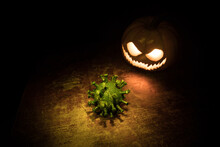 Halloween During Corona Virus Global Pandemic Concept. Glowing Pumpkins And Covid Novel On Dark With Thematic Spooky Decorations. Halloween Pumpkin On Foggy Backlight.