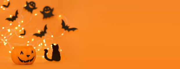 Wall Mural - Happy Halloween! Pumpkin, bats, cat, ghost on an orange background and a glowing bokeh background. Banner, copy space for text