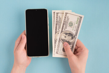 Top above first person overhead close up view photo of female hands taking money holding phone with touchscreen empty touch screen display isolated blue color background