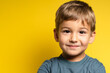 Portrait of happy joyful small caucasian boy in front of yellow background looking to the camera - Childhood growing up and concept - front view waist up copy space