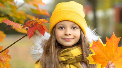 Wall Mural - Little girl with autumn yellow maple leaves.