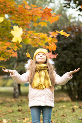 Wall Mural - Falling autumn maple leaves on a little girl.