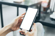 © panitan - cell phone mockup blank white screen.woman hand holding texting using mobile on desk at coffee shop.background empty space for advertise.work people contact marketing business,technology