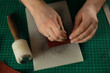 © Danil Nevsky/Stocksy - Tailor processes leather for sewing on green surface