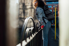 Smiling Afro Woman With Backpack Standing By Railing In City